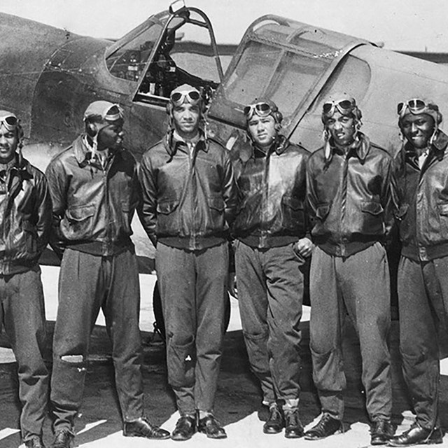 World War II Tuskegee Airmen standing in front of plane.