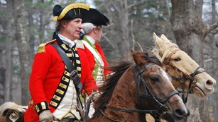 Two British officers in scarlet red coats ride horses