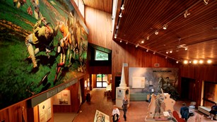 Interior of Minute Man Visitor Center. A large painting on the left wall shows a battle scene. 