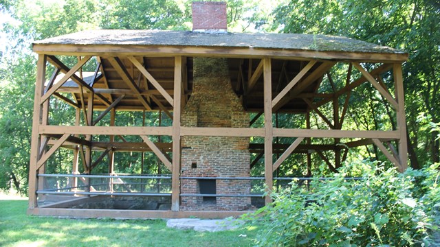 A brick chimney is surrounded by the wooden frame of a historic building