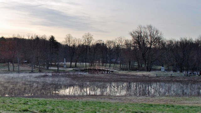 A wooden bridge spans the Concord river. Water has flooded the banks