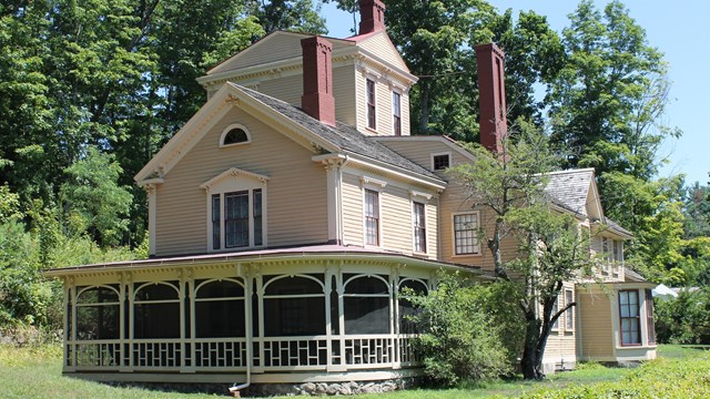 A large yellow house with multiple additions including a 3 story tower and a wrap around porch.
