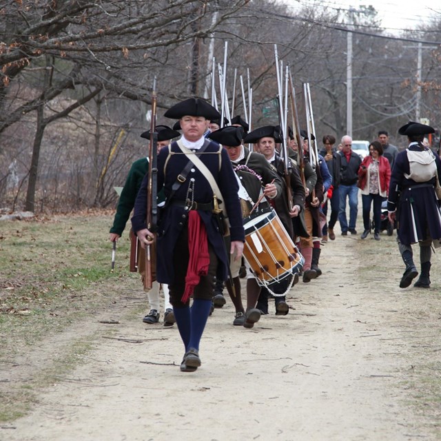 Colonial militia reenactors march down the Battle Road Trail