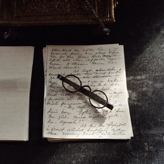 Two sheets of paper side by side, left one blank, right with writing and antique glasses on it.