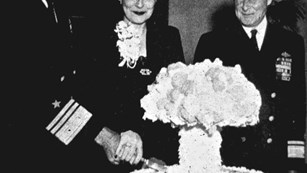 Officers and a woman cut a mushroom cloud shaped cake