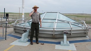 Park ranger listens to a cell phone near a glass structure