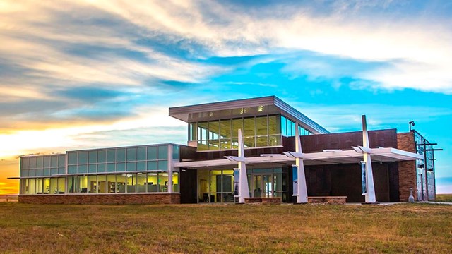 A concrete walk leads to a glass and steel building