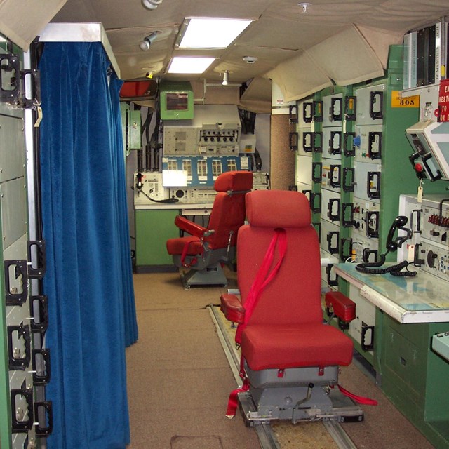Underground missile control facility. Two red chairs at control consoles. 