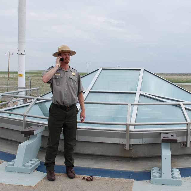 Ranger standing beside missile site listening to audio tour on his cell phone