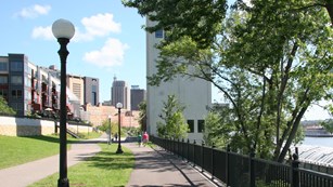 Paved hiking trail near Mississippi River with views of Saint Paul in the background. 