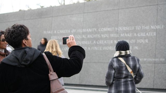Visitor taking a picture of a memorial wall with engraved quotes