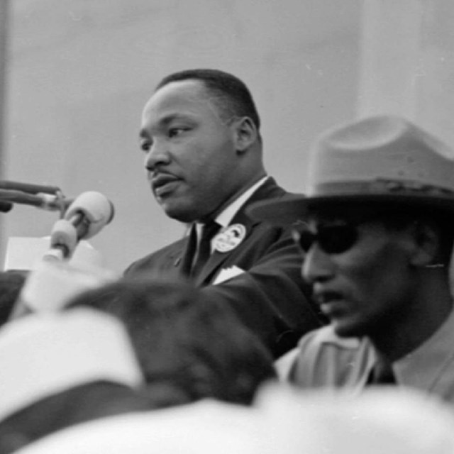 Black and white photo of Dr. Martin Luther King Jr. at a podium and park ranger in the foreground