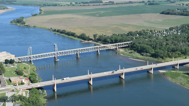 An aerial view of a wide river with two bridges on a clear day