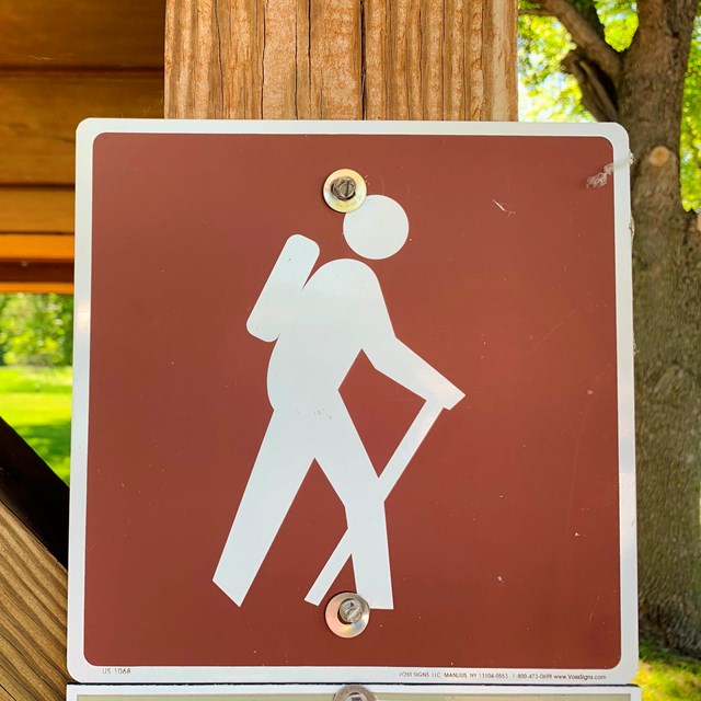 Brown sign with icon of person hiking. 