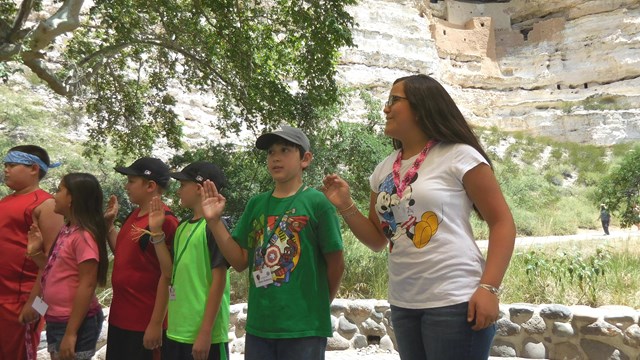 Kids standing in front of a cliff dwelling.
