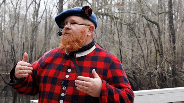 Man in Highland Plaid Clothing on a Wooden Bridge
