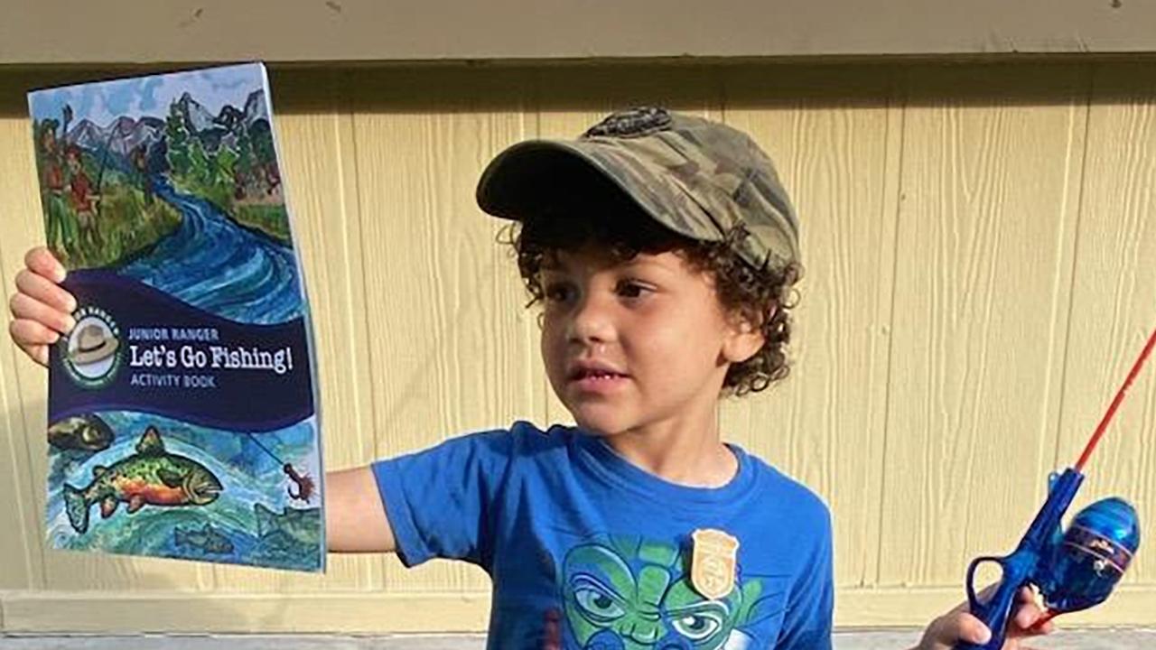 Young visitor holding a Junior Ranger booklet and fishing pole