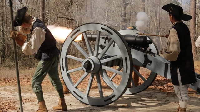 Group of living historians firing a cannon. Big muzzle blast coming out the end of the cannon
