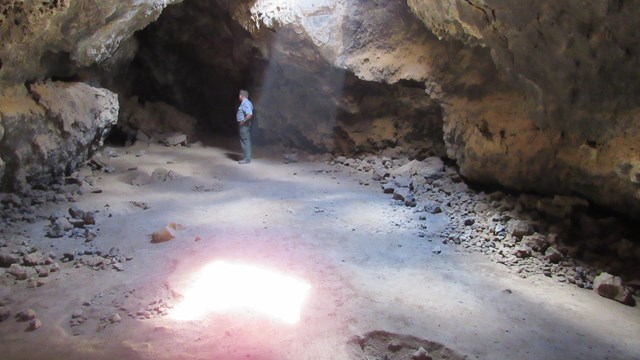 A beam of light and a park ranger in an underground lava tube 