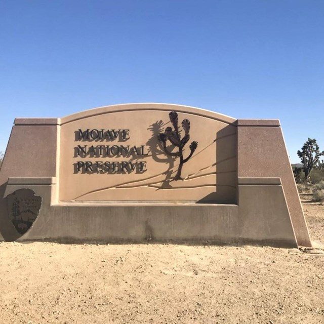 Mojave National Preserve Welcome Sign on Kelbaker Road with snow in the mountains on a cloudy day