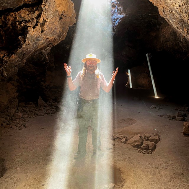 A ranger bathed in a beam of light in the Lava Tube.