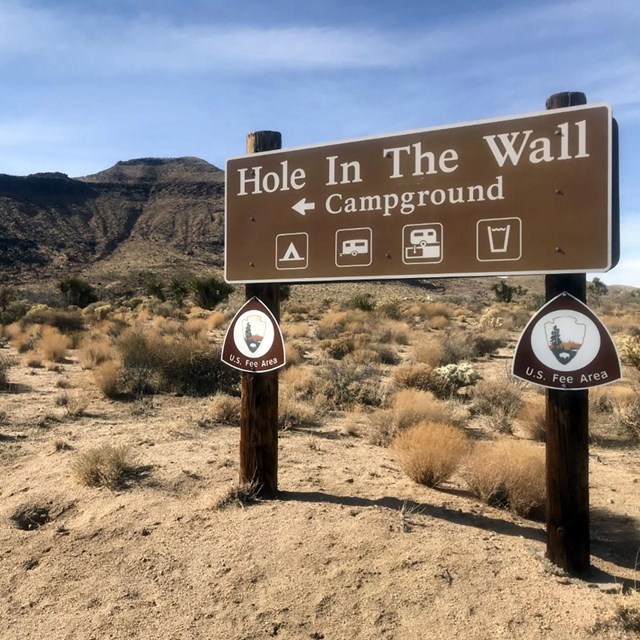 Picnic table, fire pit, and desert bluffs at Hole-in-the-Wall Campground