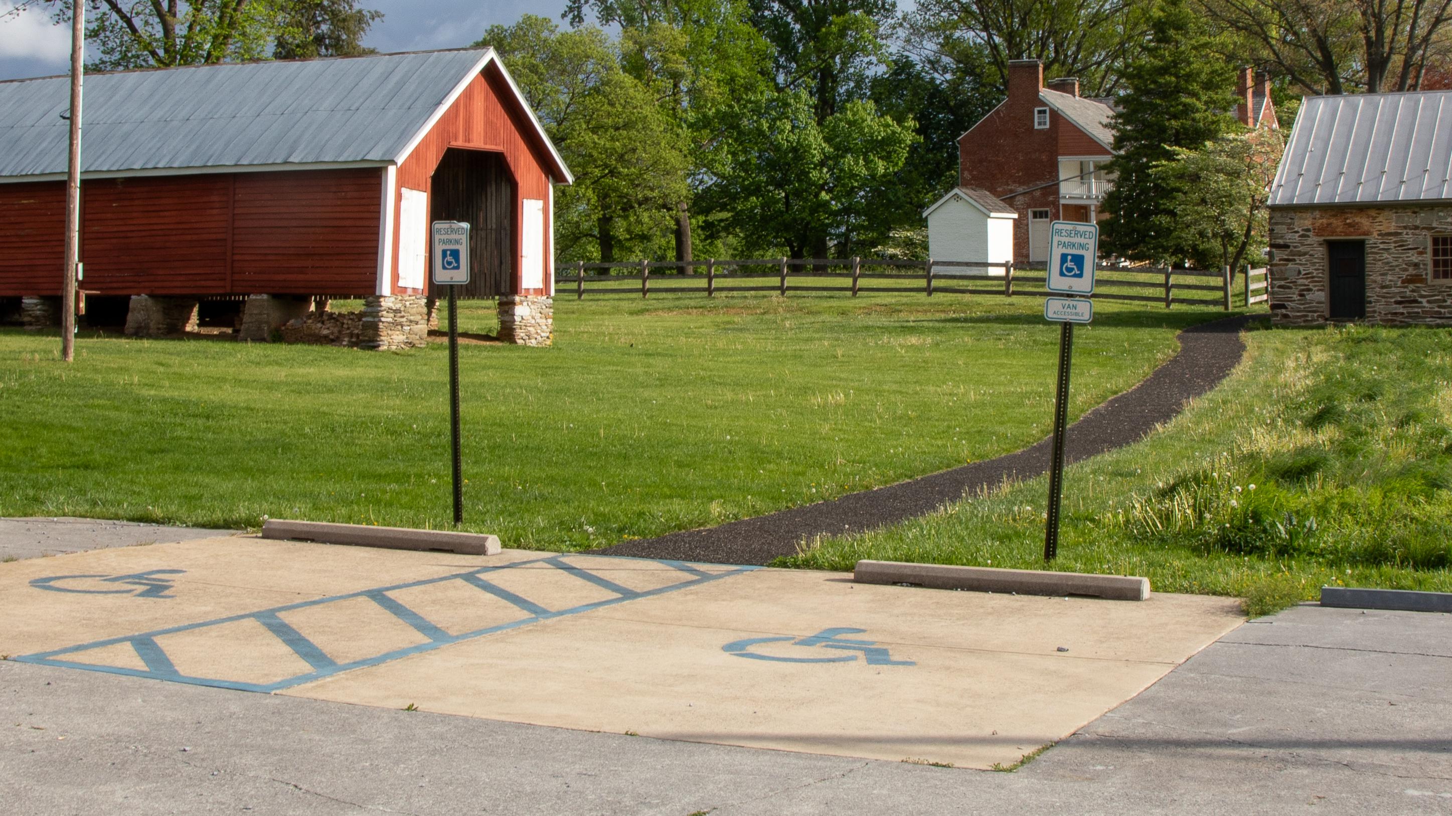 Two signed accessible parking spaces with an access aisle on the edge of a parking area.