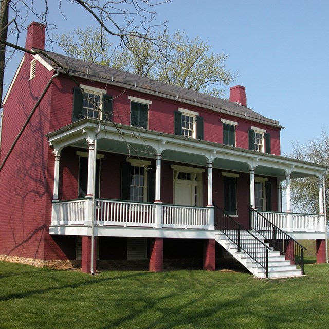 Two-story, red brick farm house with porch along the front.