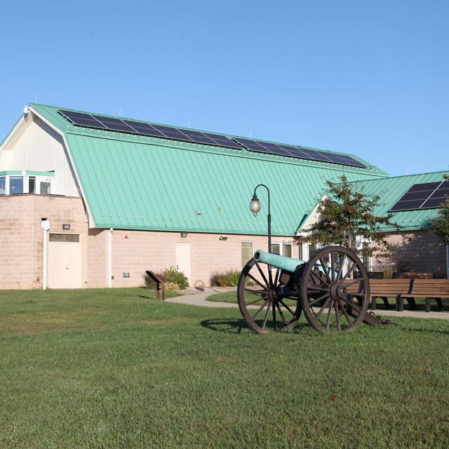 A barn-shaped building with a cannon displayed out front.