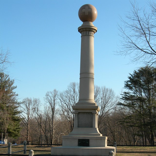 A tall stone column with a round ball at the top.