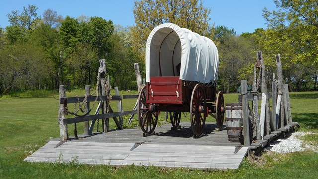 A covered wagon in a grassy field.