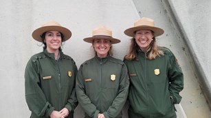 Three park rangers stand next to each other.