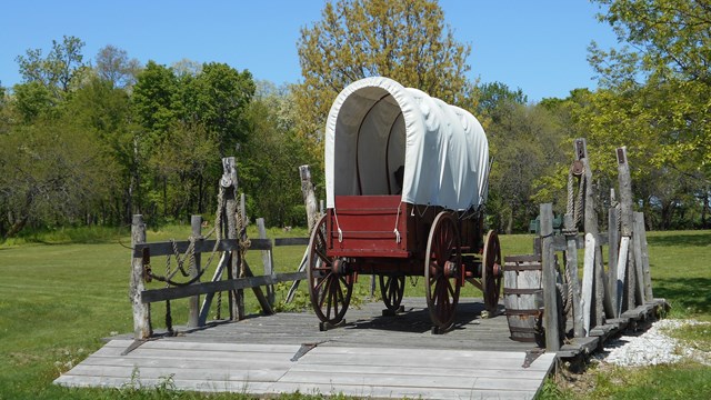 A large covered wagon on a green grass lawn.
