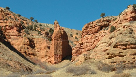Red, sandstone cliffs, highly-eroded, with an eroded ravine.