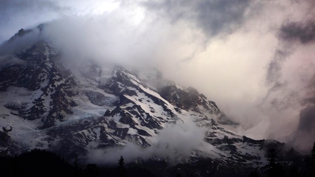 Dark clouds swirl around a mountain peak. 