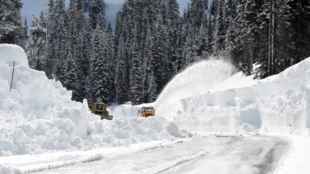 Two rotary plows clearing snow from a road.