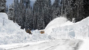 Two rotary plows clearing snow from a road.