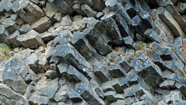 A cliff of roughly octagonal columns of grey rock.  