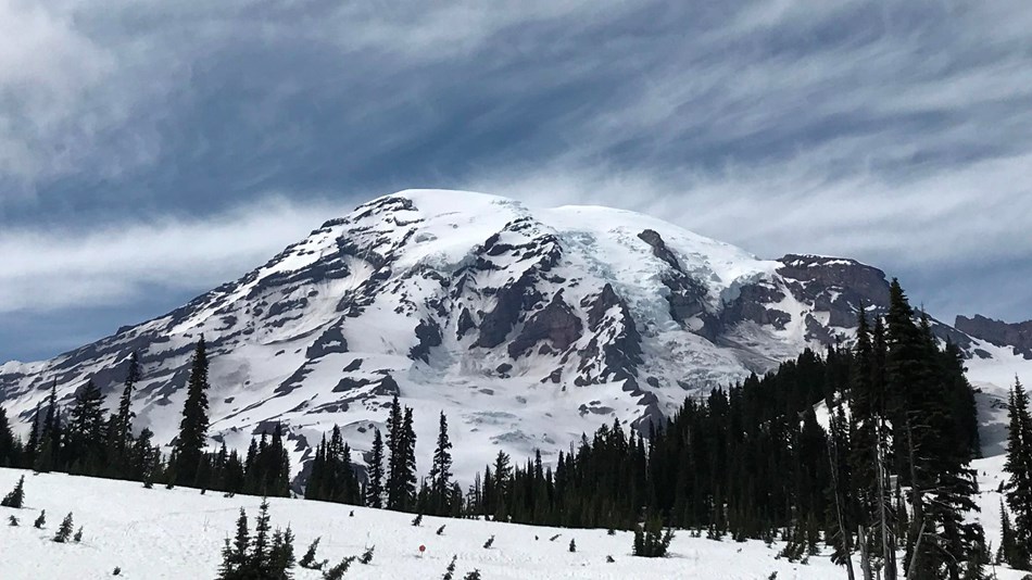 Mount Rainier against a cloud-streaked blue sky.