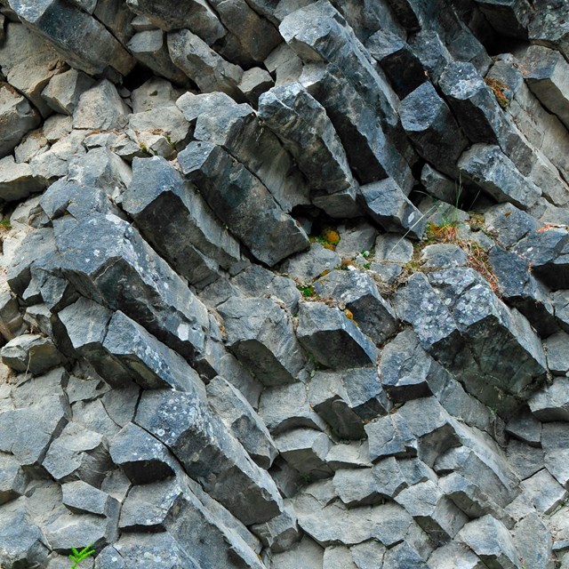 A cliff of roughly octagonal columns of grey rock.  