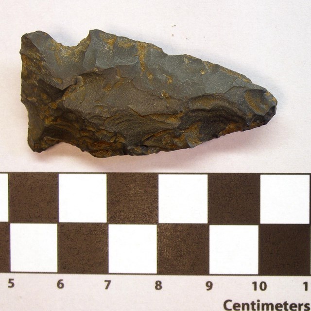 Two stone arrowheads on a white backgroun with a ruler below