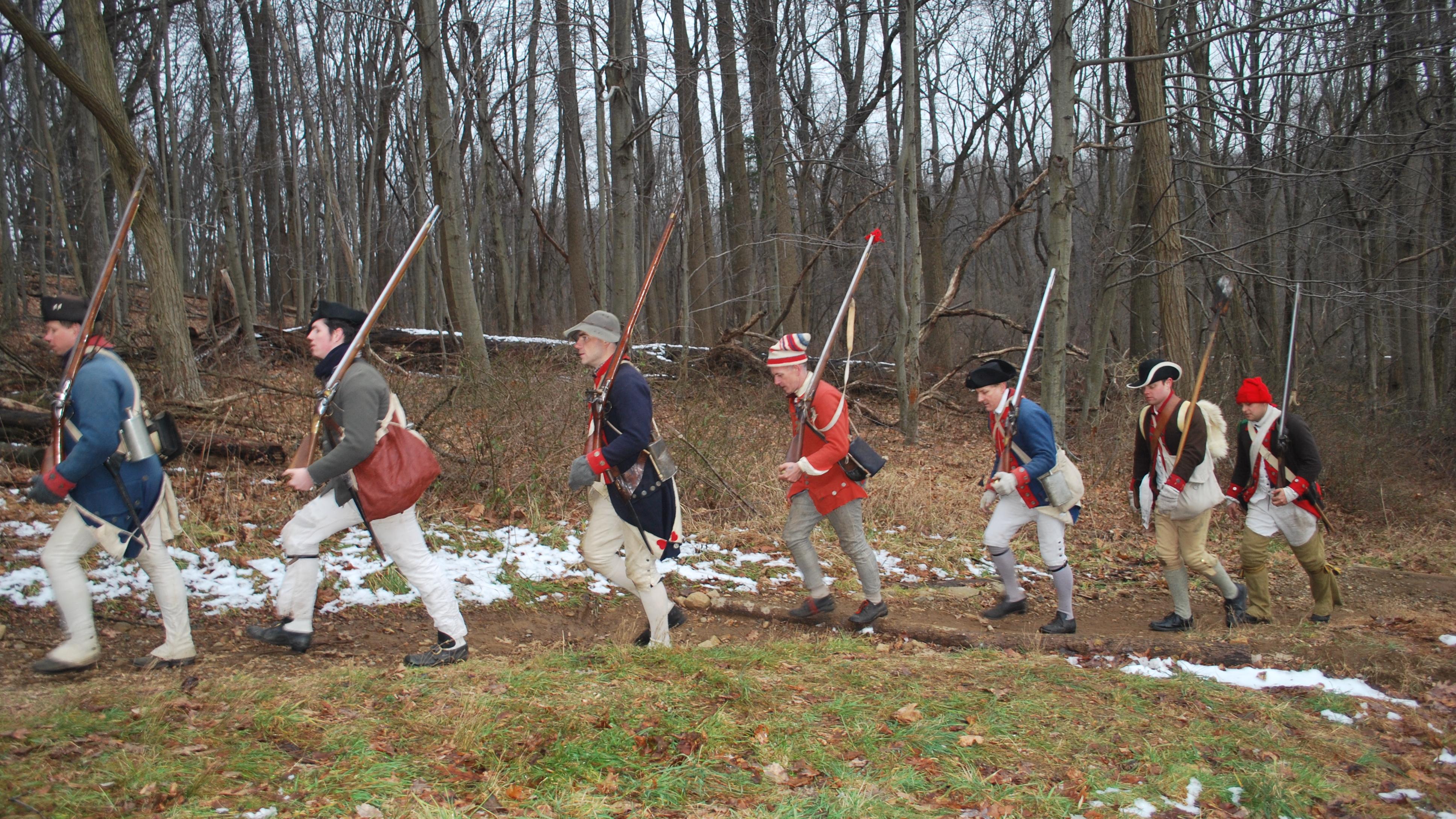 Soldier reenactors marching along a trail in the forest