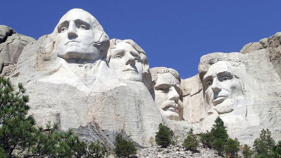 Close up photo of Mount Rushmore under a clear blue sky.