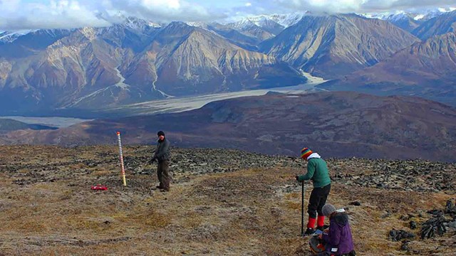 Researchers install equipment on a mountain top.