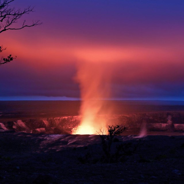 Glow from an active volcano reaches up into the clouds.