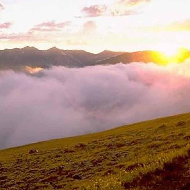 Clouds fill a mountain valley at sunset.