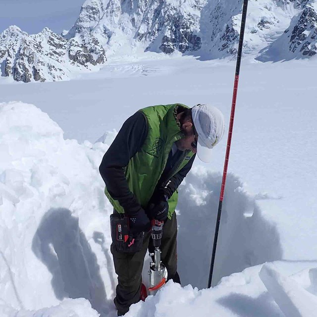 A researcher taking measurements in a snow pit.