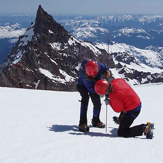 Two researchers take measurements on a glacier.