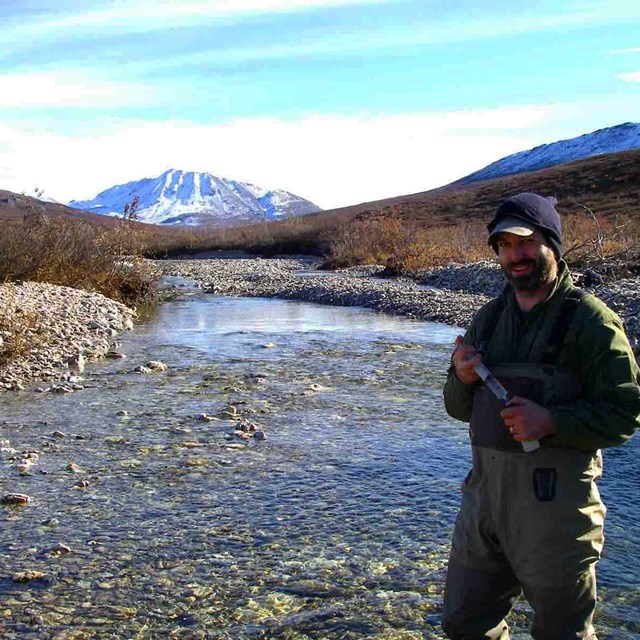 A researcher collects water samples from an Arctic stream.