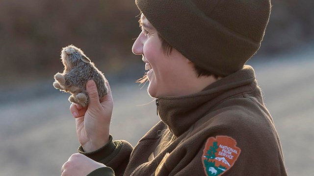 NPS employee holds stuffed animal while laughing